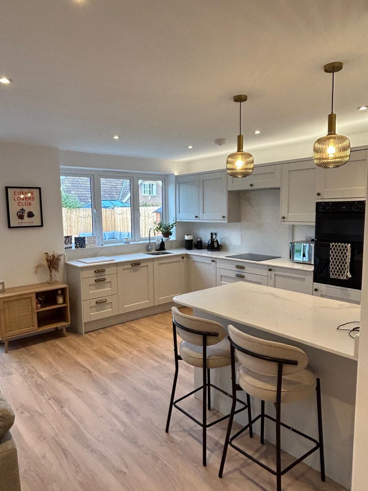 Shaker kitchen with a quartz breakfast bar, brass pendant lights and a marble splashback, fitted by FR Carpentry