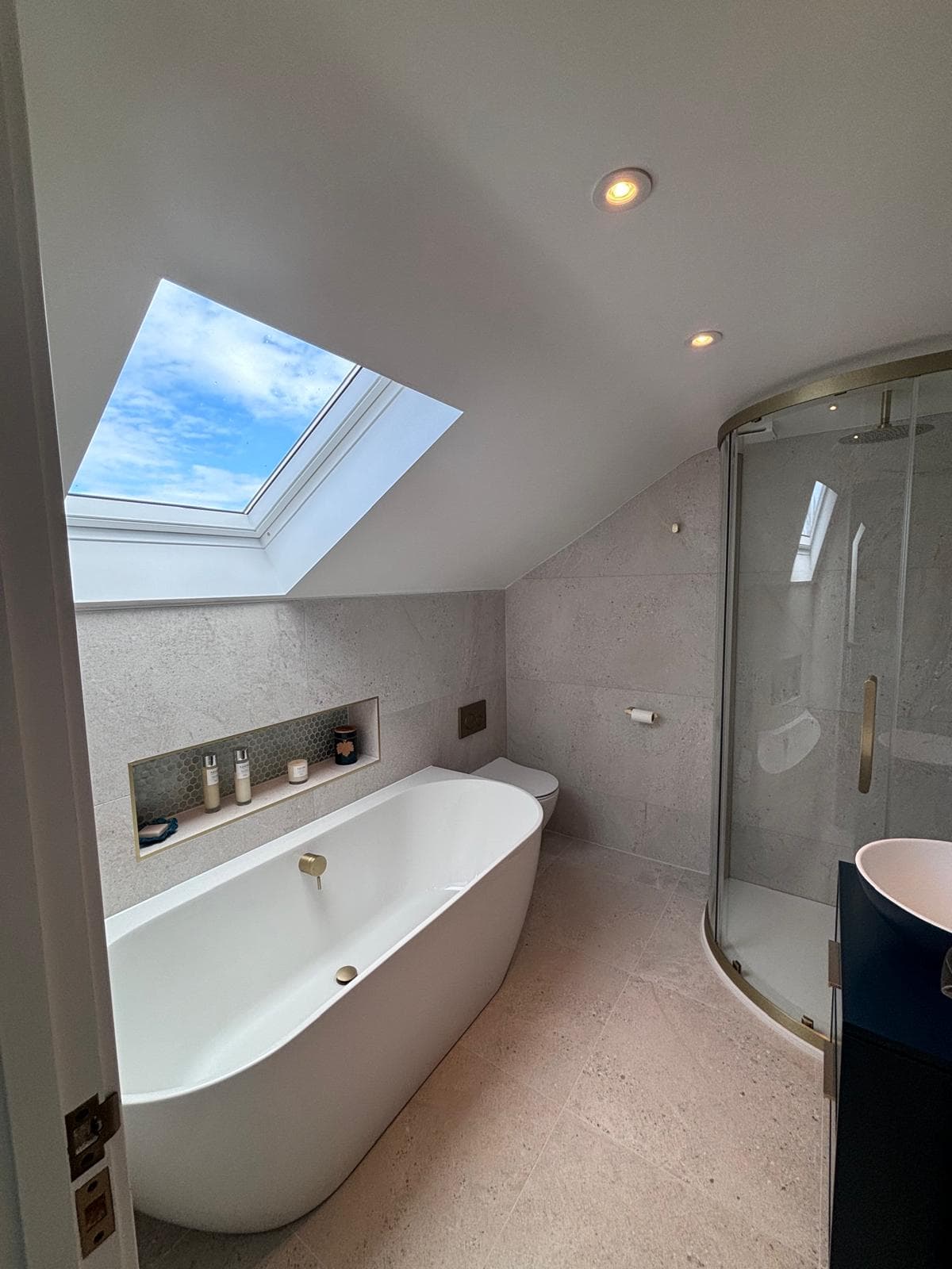 Loft en-suite with a Velux rooflight, freestanding bath, curved shower and brass fittings