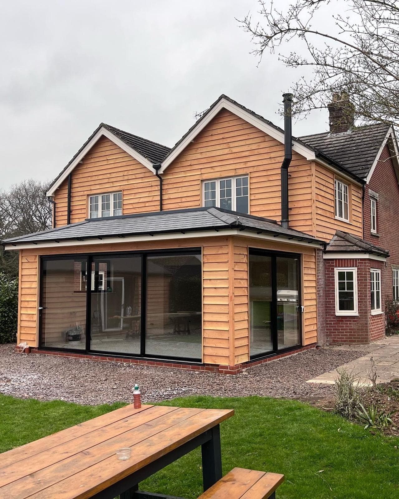 Green-oak framed extension with corner glazing and cedar cladding on a period cottage
